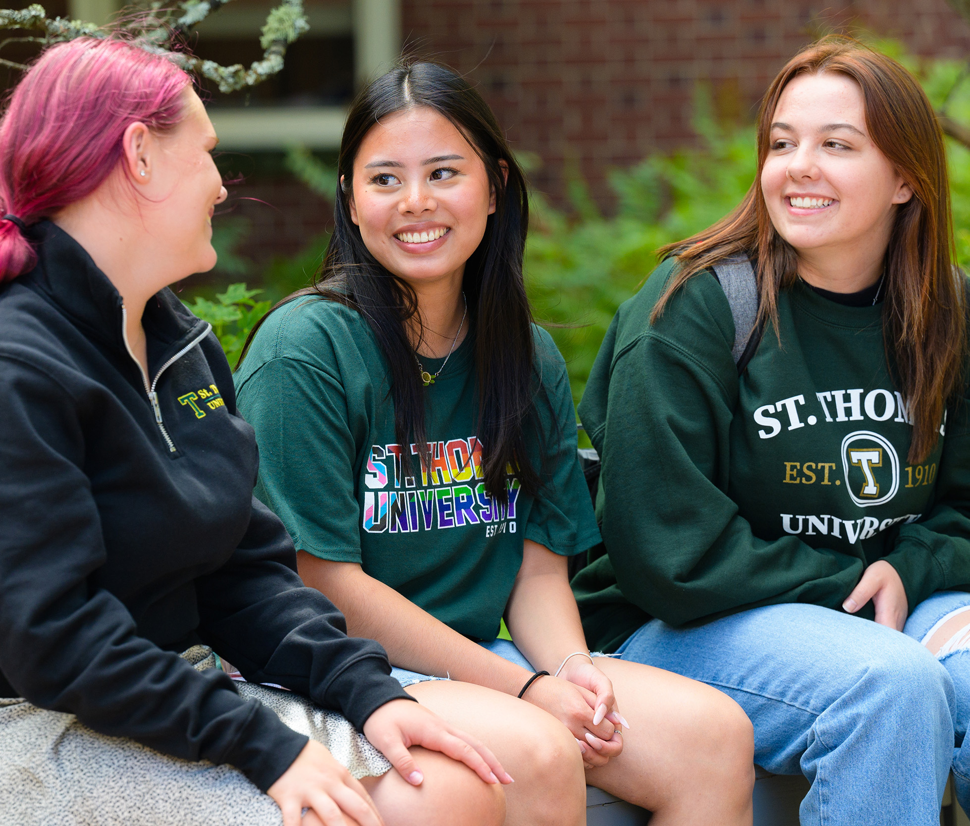 Three female students sitting on a bench on STU campus