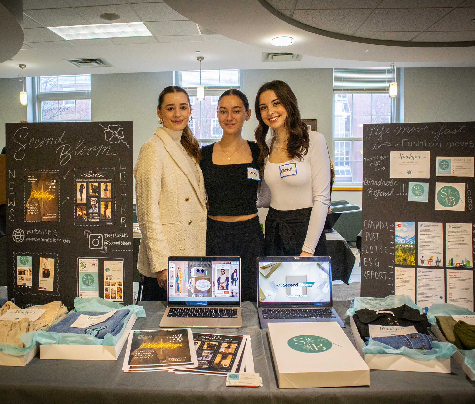 A group of students standing behind their presentation for Second Bloom — a social enterprise project that repurposes clothing to address the fast fashion industry