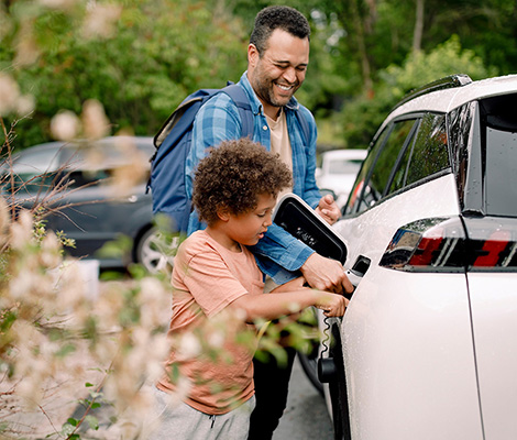 Photo of a man and a little boy gassing up a white car