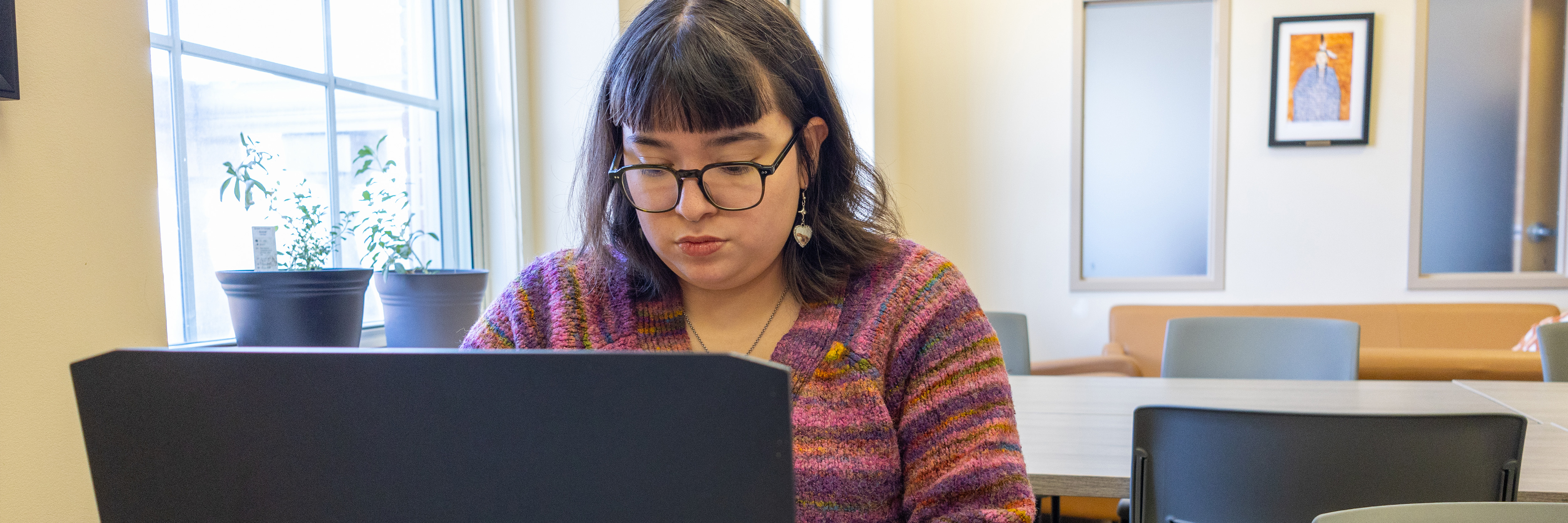 An Indigenous student sits in the Wabanaki Centre working on their laptop