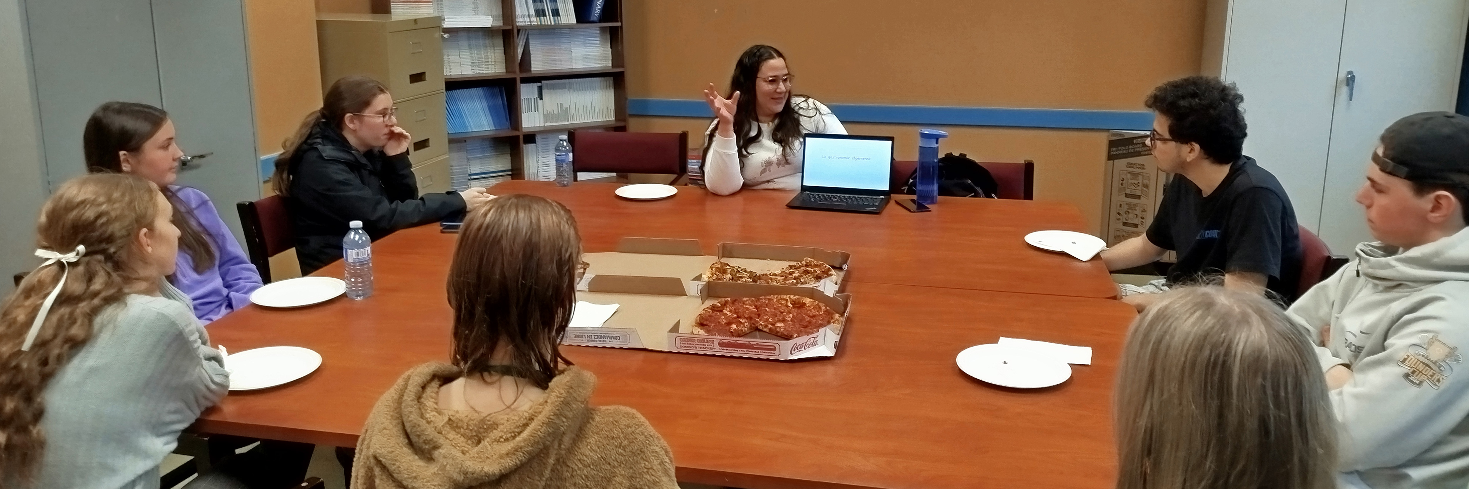 A group of students sit around a large table having a discussion