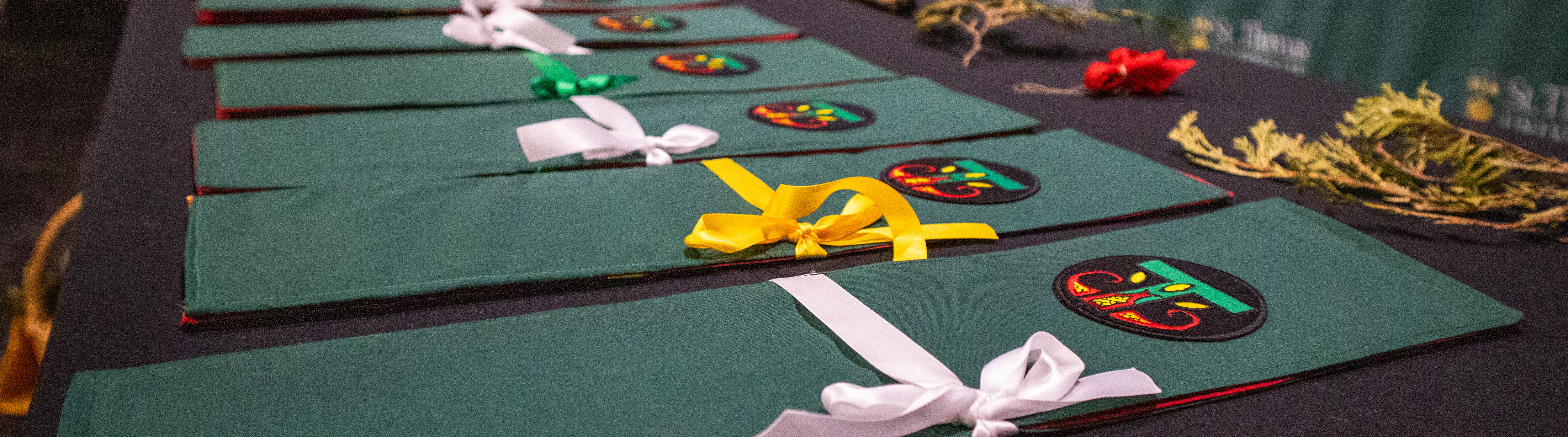 The table set up at the Eagle Feather Ceremony featuring embroidered feather carriers with the Indigenous T logo