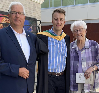 Graduate standing with supporters after Summer Convocation