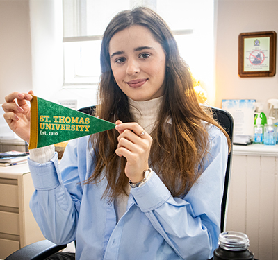 Student intern holding STU pennant sitting at desk at internship site