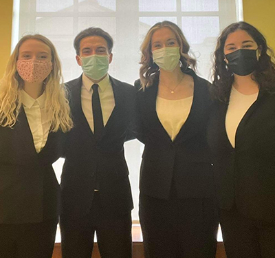 Four students standing together in a classroom