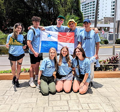 Group shot of STU students in Panama - with students holding Panama flag and one student with STU pennant