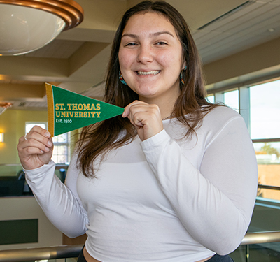 Student holding STU pennant in the second floor of the Study Hall