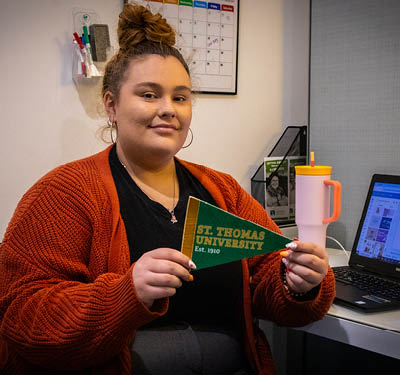 student intern holding a STU pennant