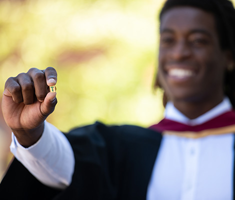 STU grad wearing robe holds up T-Pin