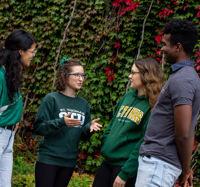 A photo of four students talking on campus in the fall