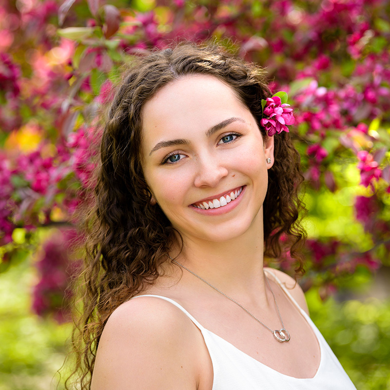 A student standing in front of the apple blossoms on campus