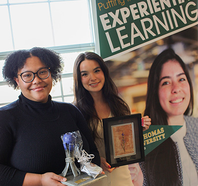 STUdents Chante Laverlot and Jazna Ward stand together holding up their respective FutureNB and FutureWabanaki Student Excellence Awards in front of an Experiential Learning Banner.