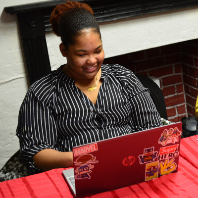 A photo if a student sitting at a table working on her laptop