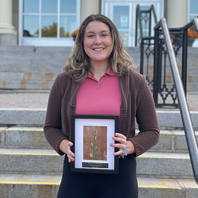 STUdent Juliane Martin stands in front of GMH holding her award