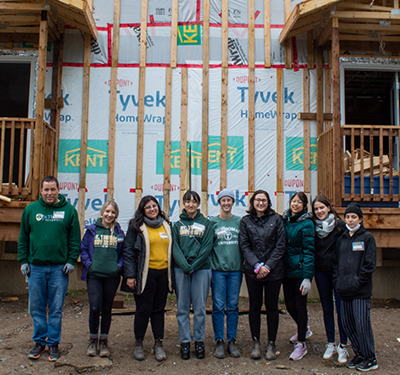 Students standing in wood frame home under construction