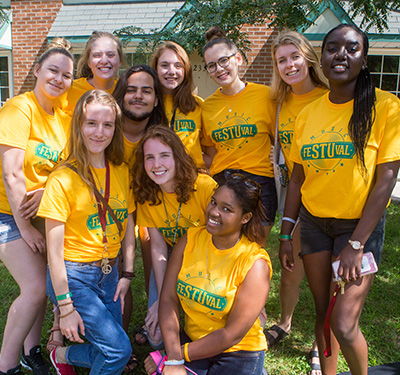 A group of student wearing gold STU t-shirts standing outside smiling