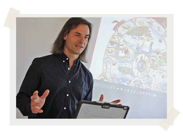 Dr. Derek Simon teaching a class with a projector in background