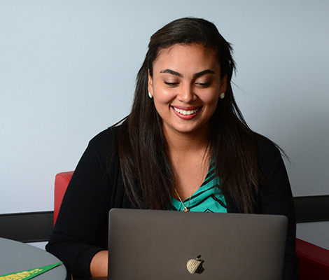 A student sitting with a laptop and a STU banner on the table