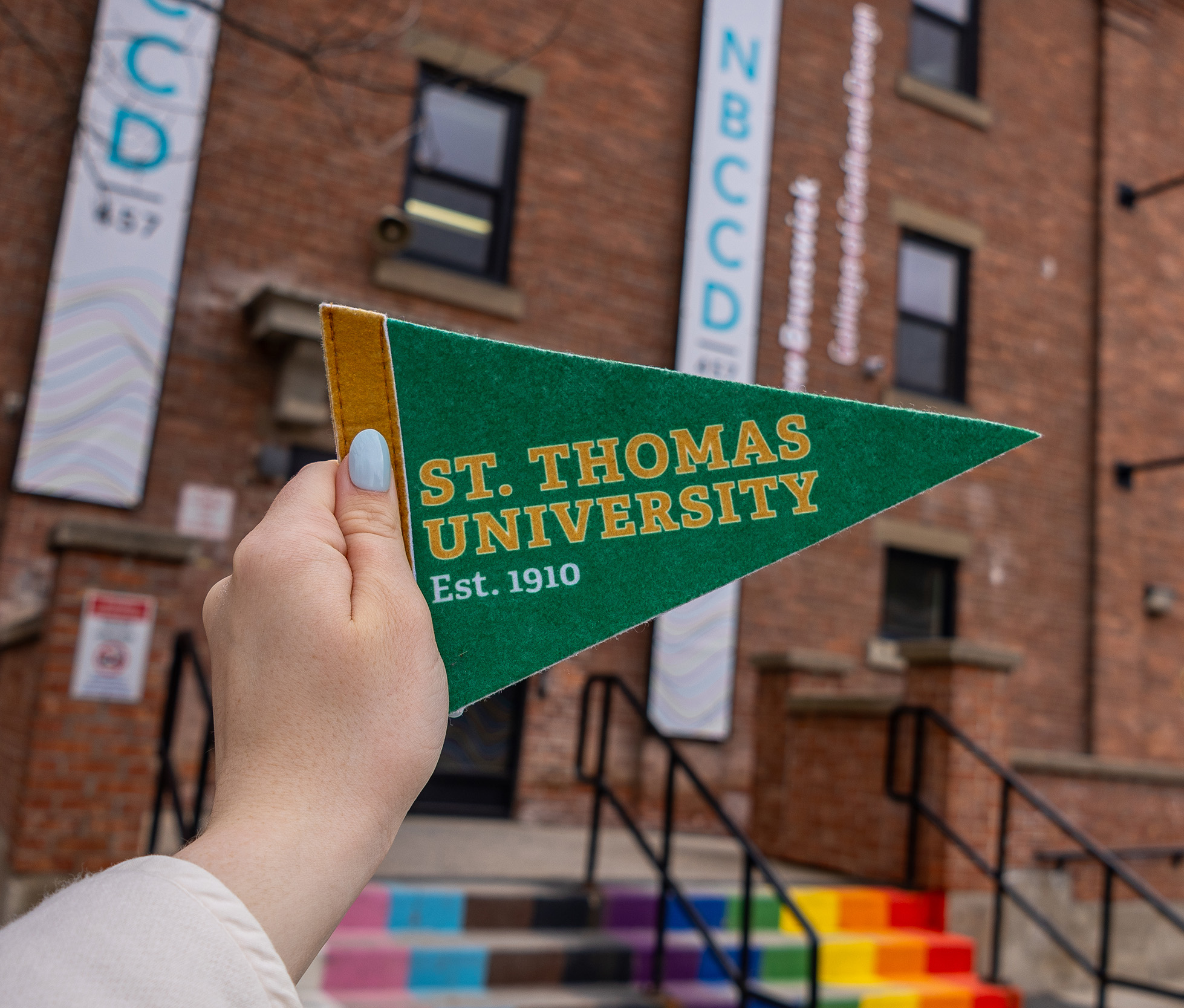 A close up of the STU Pennant, being held in front of NBCCD, which STU has partnered with for a new Interdisciplinary Major in Humanities.