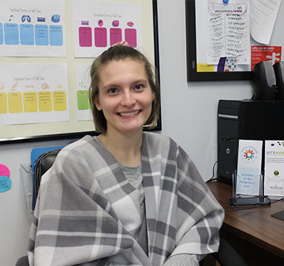 A student sitting in from of a computer looking at the camera