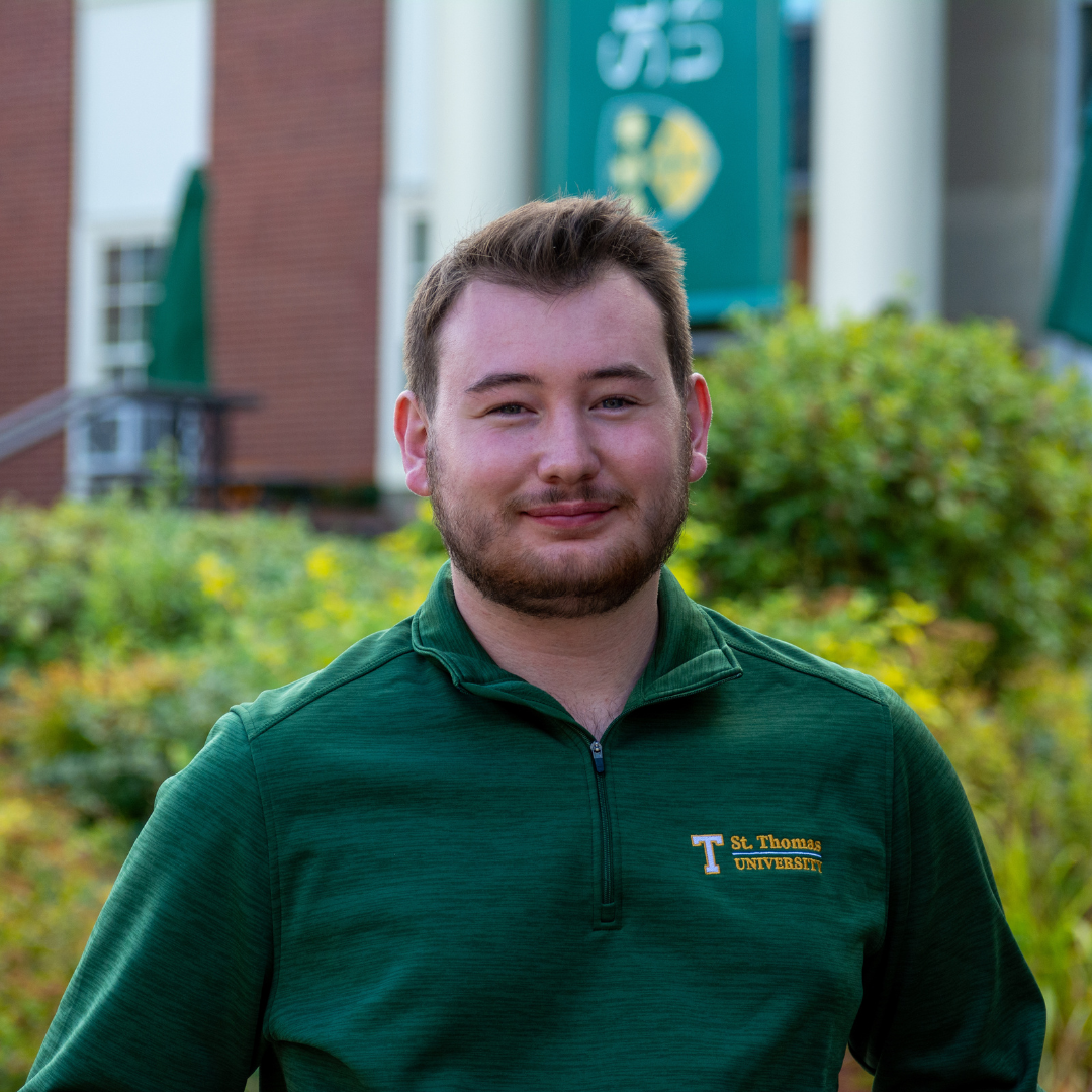 Evan smiling in front of campus