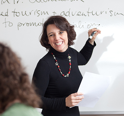 A smiling professor writing on a whiteboard