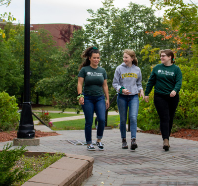 Three students walking on campus outdoors